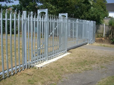 A galvanized palisade sliding gate for a place is closed, some sections of the gate are overlapped with the palisade fence.