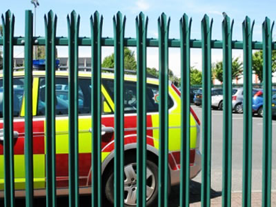 Green triple pointed palisade fence with W pale section serves as the fence for the parking lot.