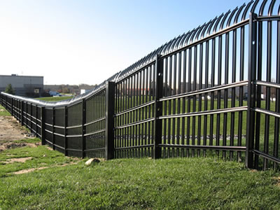 On a vast grassland, a row of high palisade fence follow the uneven terrains, the top of the fence is bending.